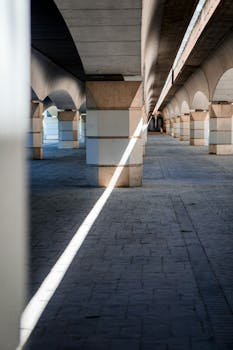 A concrete underpass with symmetrical arches and a beam of sunlight creating a striking visual effect.