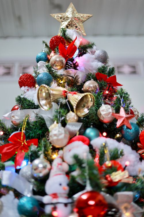 Free Vibrant Christmas tree decorated with ornaments, ribbons, and star topper. Stock Photo