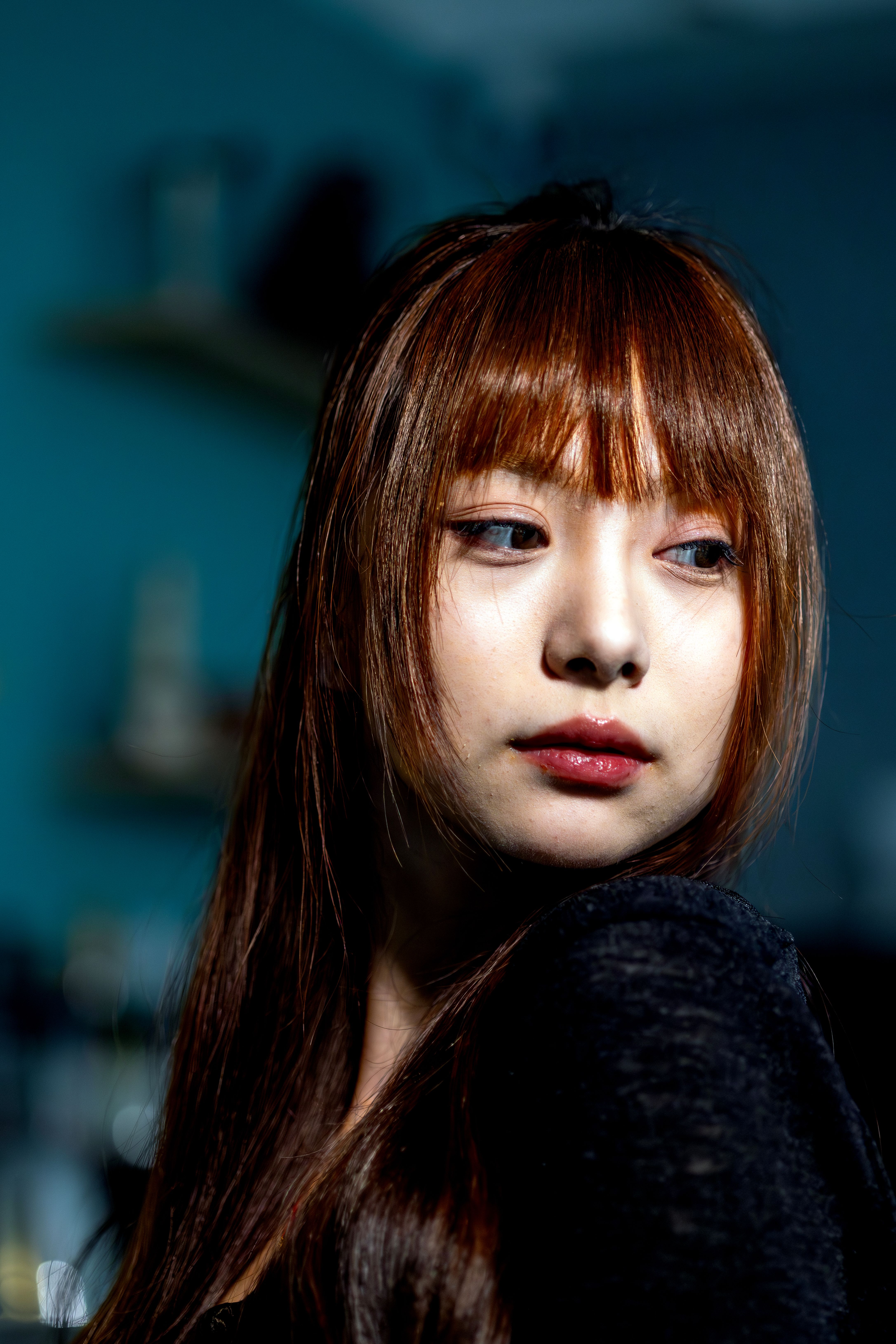 Captivating indoor portrait of a young woman with dramatic lighting and a pensive look.
