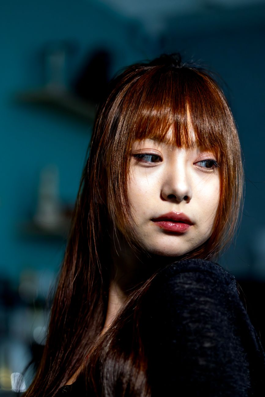 Captivating indoor portrait of a young woman with dramatic lighting and a pensive look.