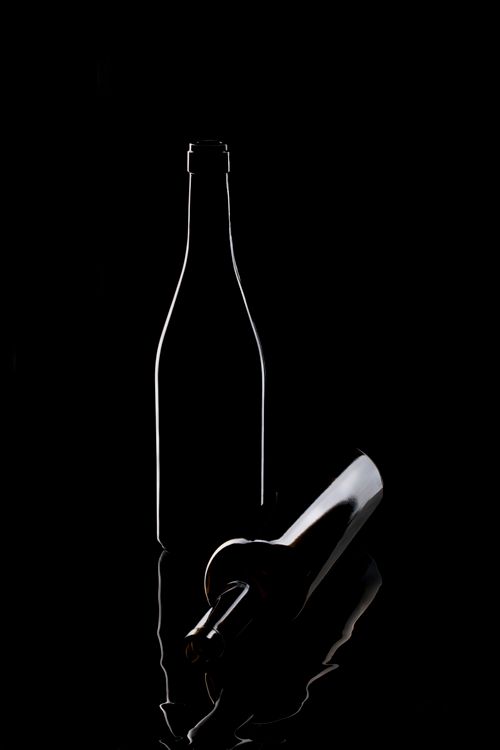 Free Artistic silhouette of two wine bottles against a dark background, highlighting shape and reflection. Stock Photo
