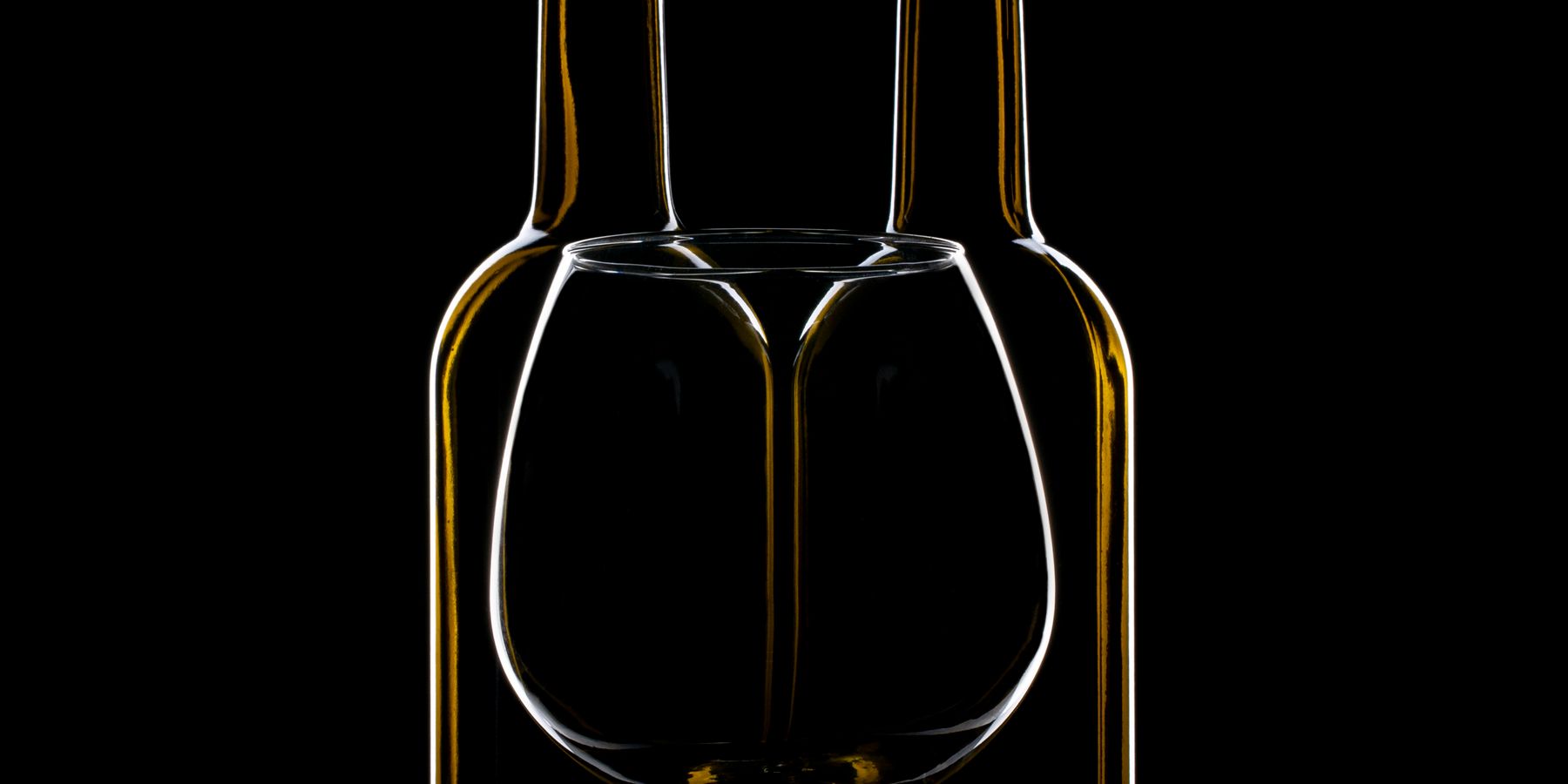 The silhouettes of two wine glasses against black