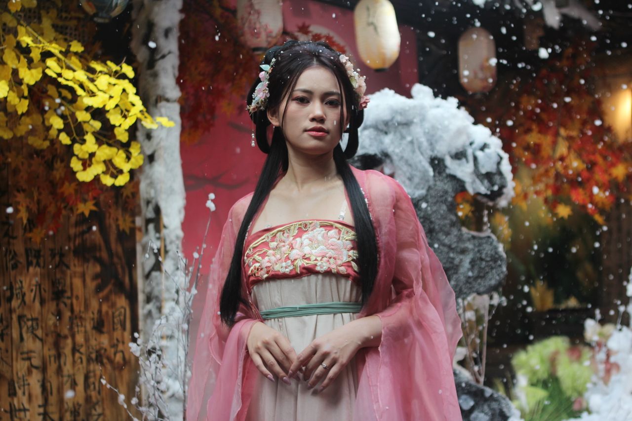 a woman in traditional asian dress amidst an autumn themed garden sett