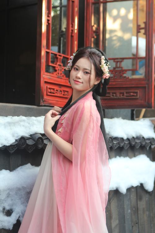 Free Young woman in traditional Chinese dress poses gracefully in a snowy courtyard setting. Stock Photo