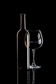 Stylish shadow of a wine bottle and glass on a black background, creating an elegant and minimalistic vibe.