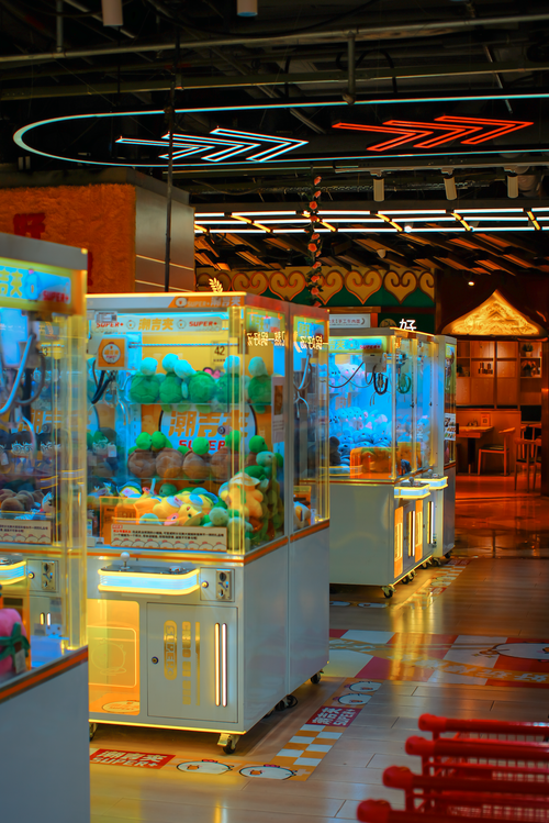 Free Vibrant rows of claw machines in a lively indoor arcade setting, filled with plush toys. Stock Photo