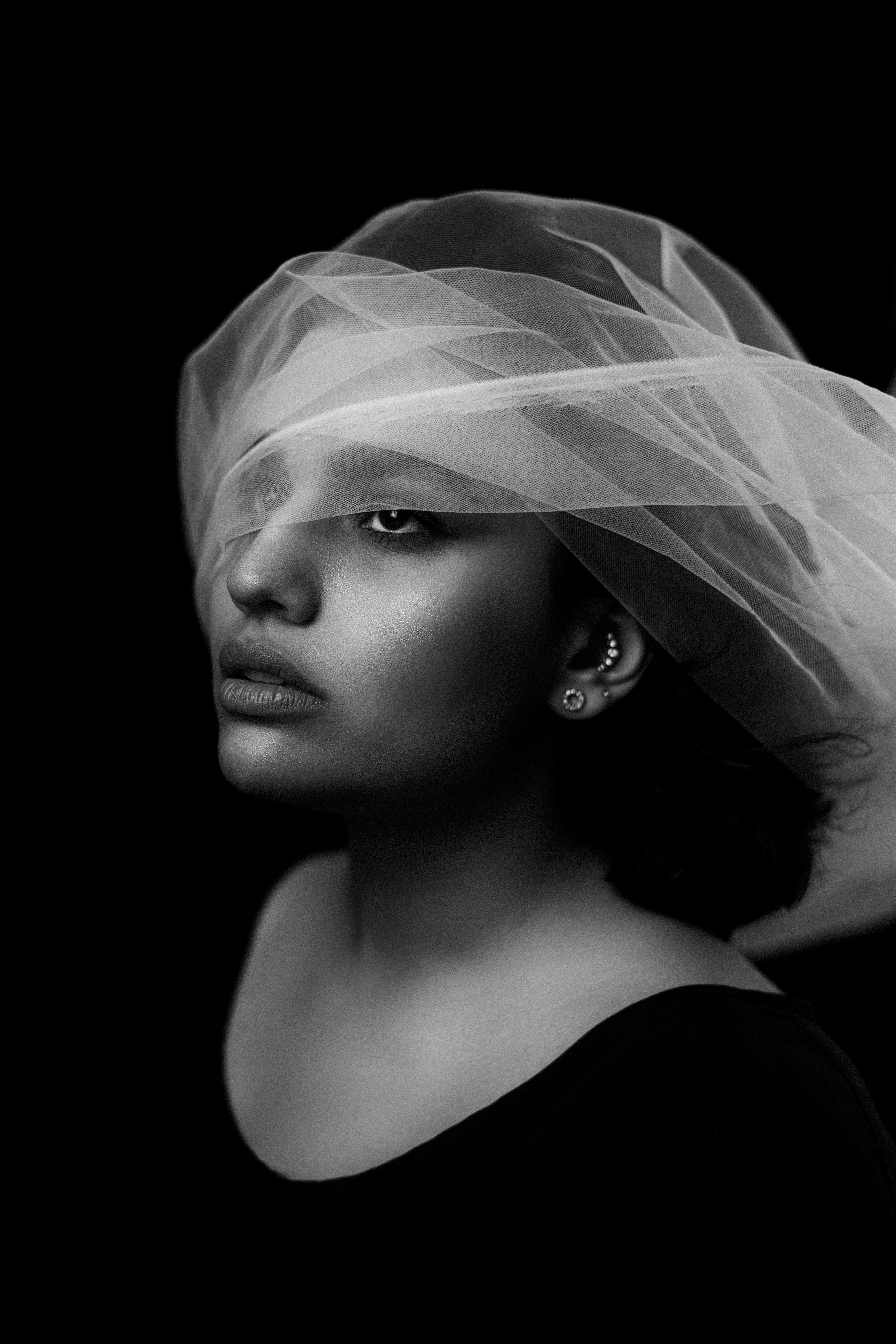 Artistic black and white portrait of a woman with sheer fabric, exuding elegance and mystery.