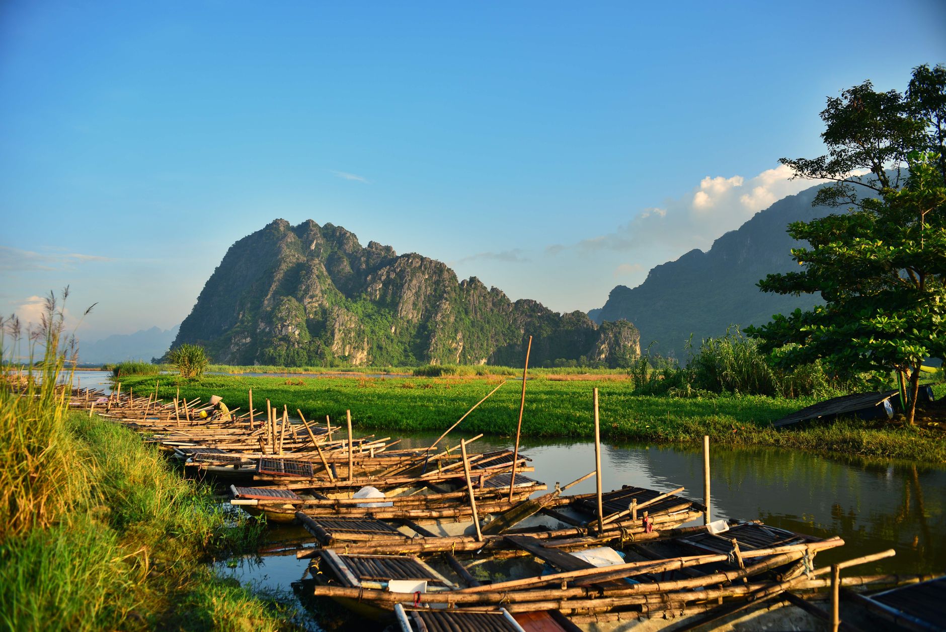 Breathtaking river scene with bamboo rafts and lush mountains under a clear blue sky.