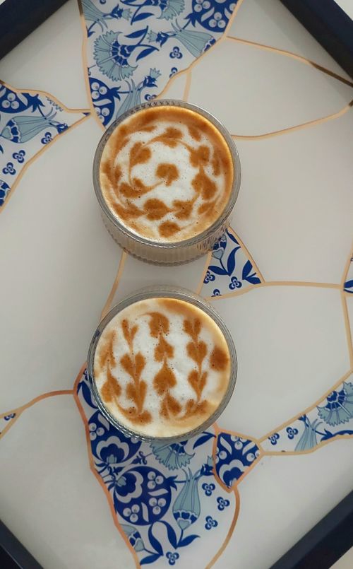 Free Two cappuccinos with latte art served on a beautifully tiled table, creating an artistic and inviting scene. Stock Photo