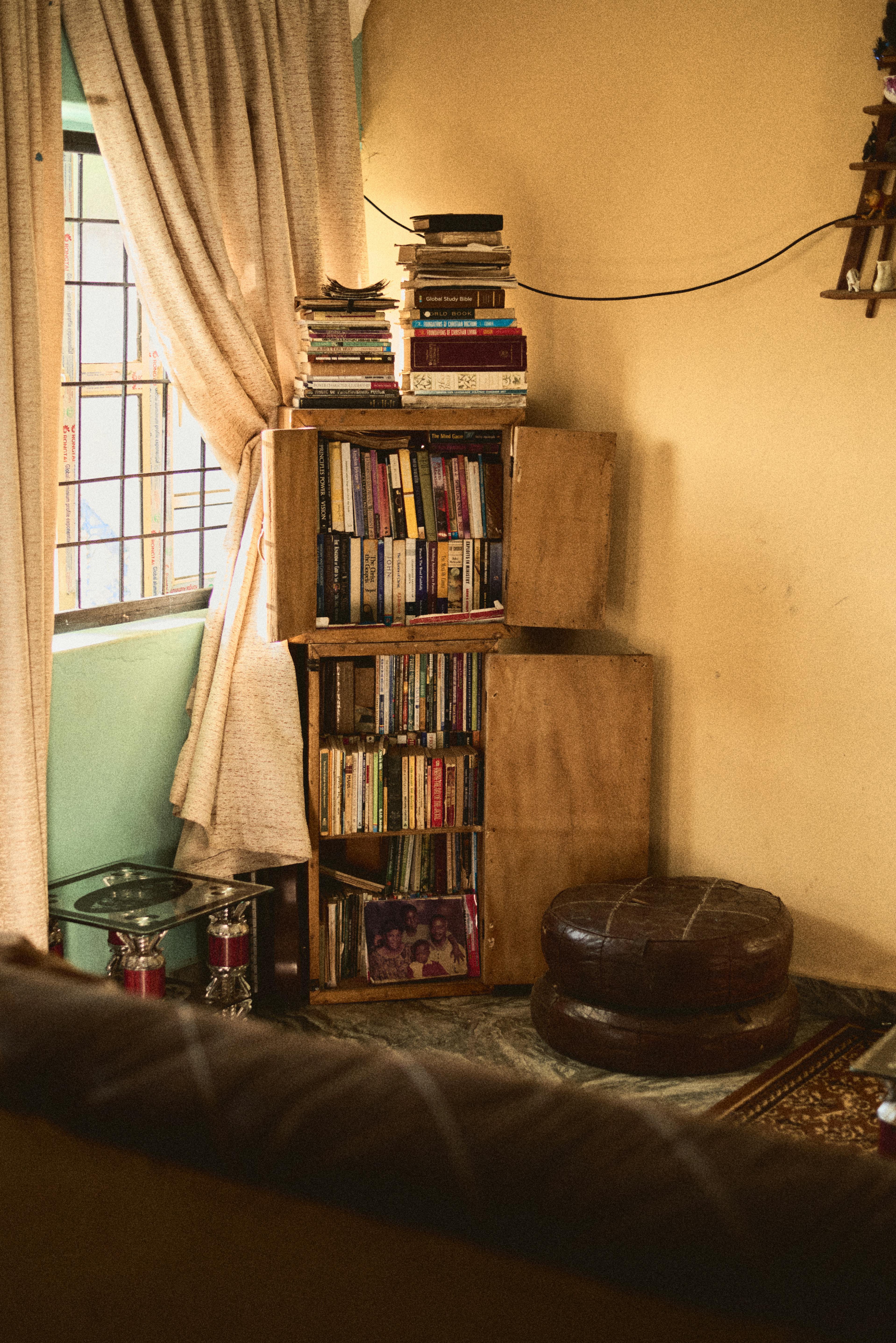 Free A cozy living space with a bookshelf filled with books in a Nigerian home. Stock Photo
