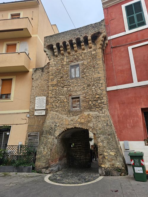 Free Ancient stone gate nestled between modern buildings in a European town. Stock Photo