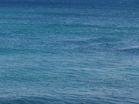 A serene view of calm ocean waves with varying blue hues, perfect for backgrounds or nature themes.