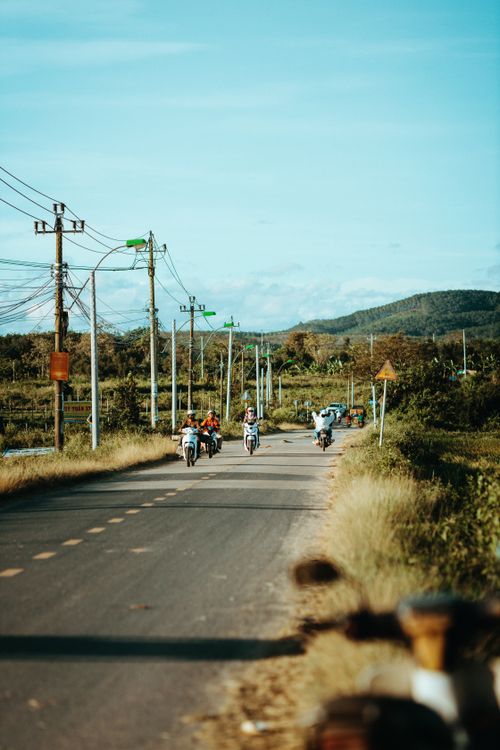 Free A scenic rural road in Kon Tum, Vietnam featuring motorcyclists and lush greenery. Stock Photo