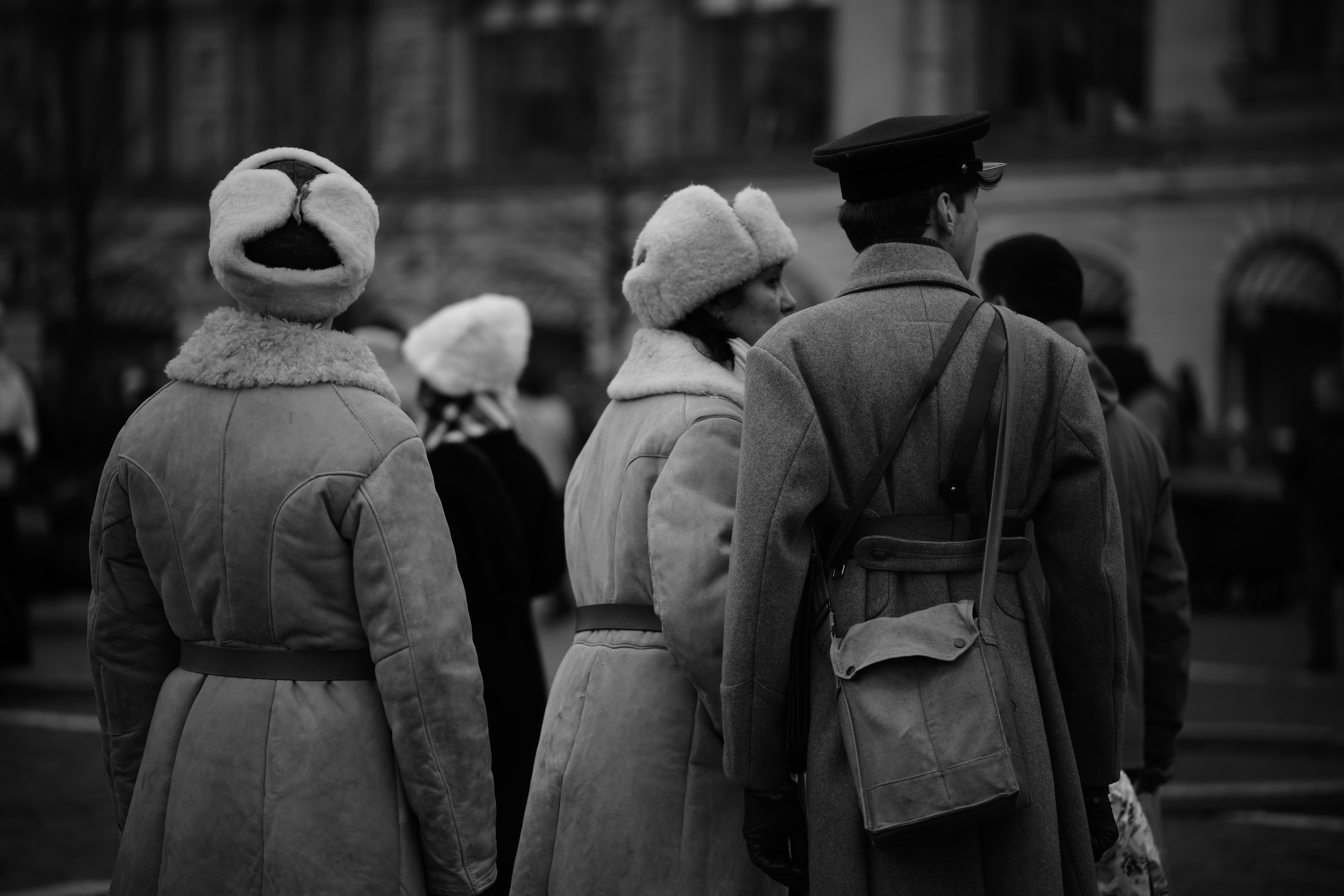 Group of people in vintage winter clothing outdoors, black and white photo.