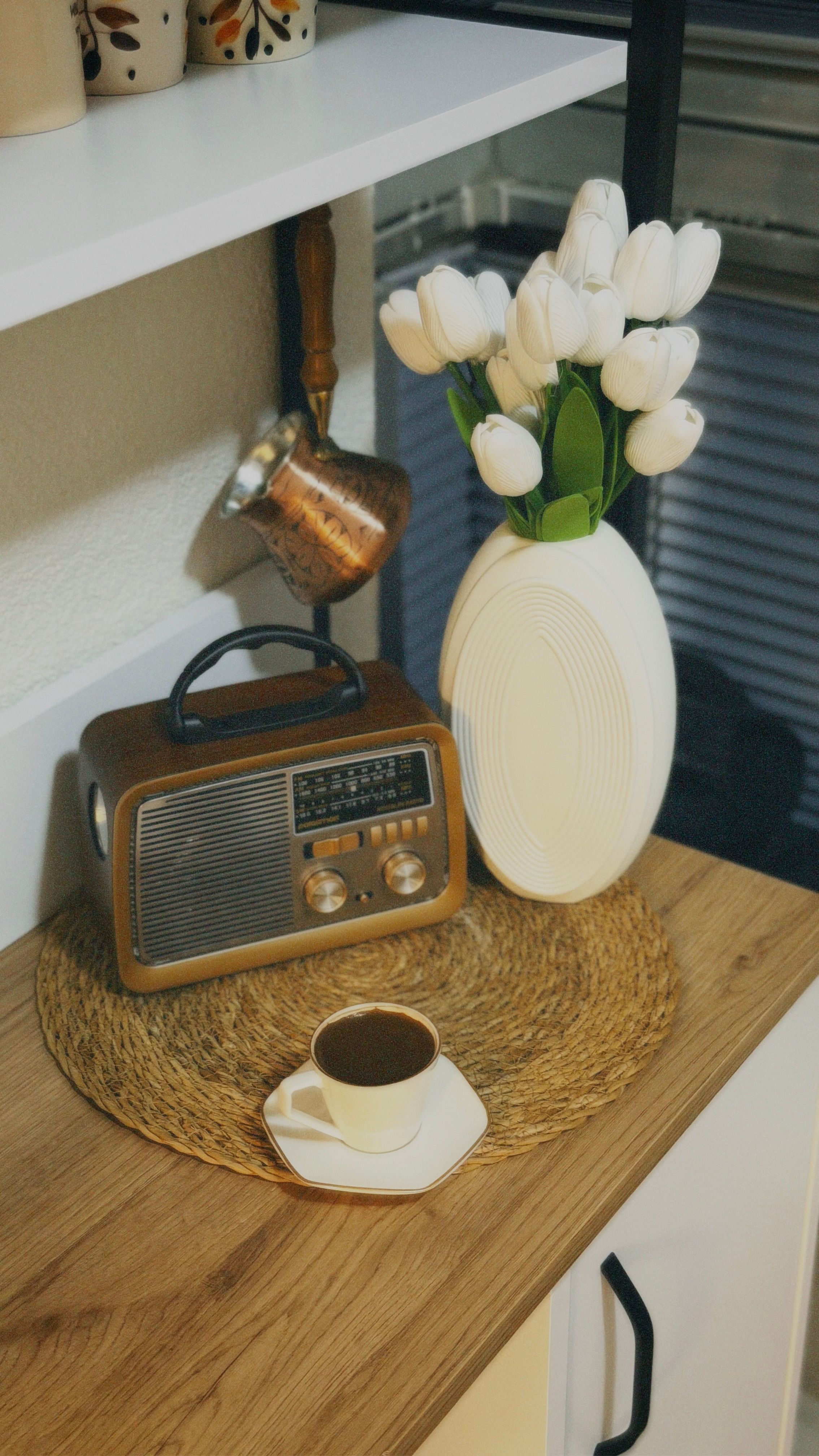 A retro wooden radio on a kitchen worktop beside a white vase