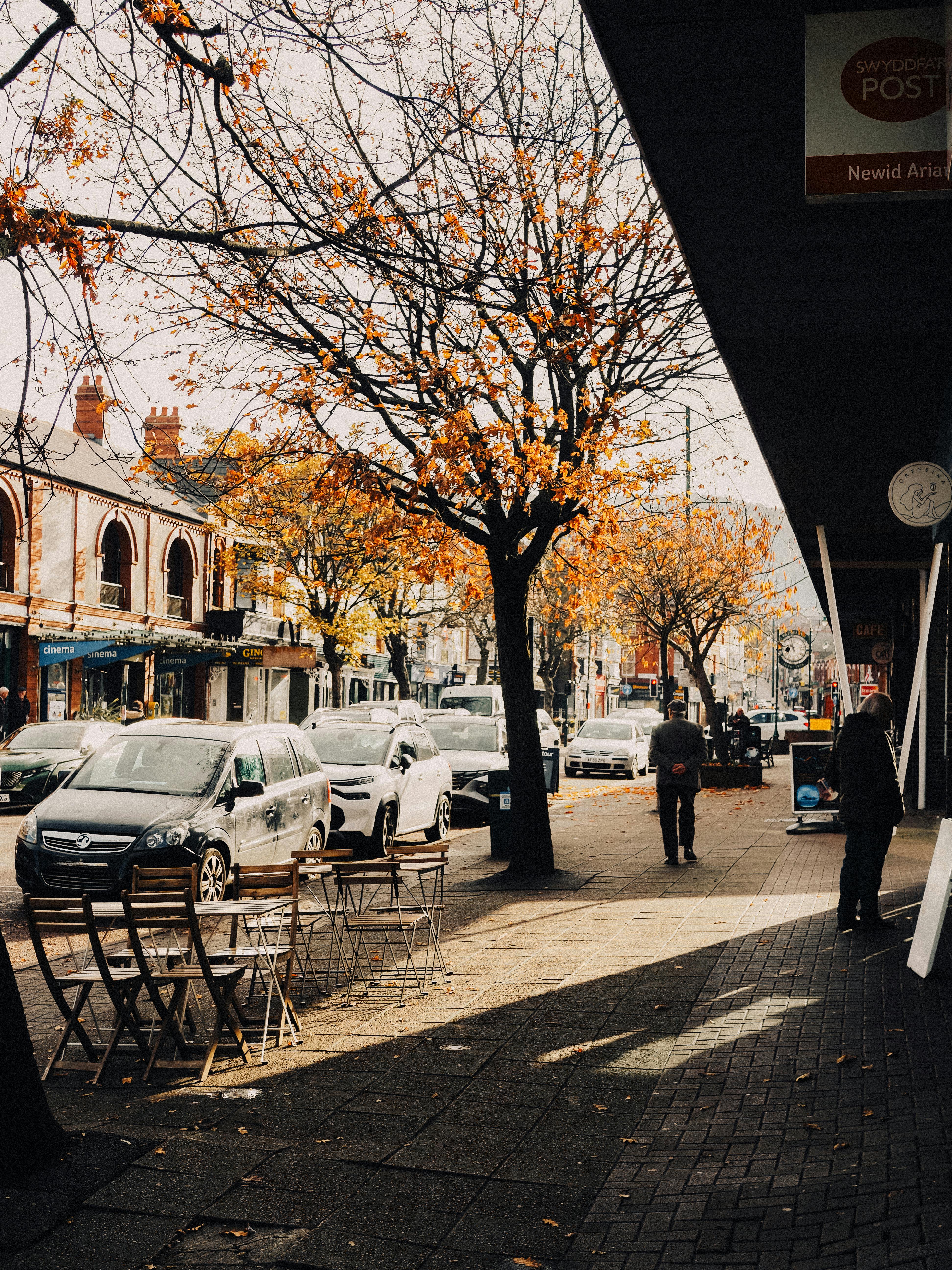 Bustling autumn street scene in Prestatyn, Wales with cafes and cars.