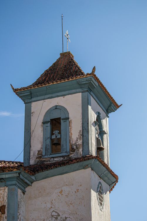 Free Rustic church tower with a bell, cross, and azure sky background. Stock Photo