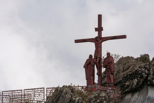 Free A hilltop crucifix with religious statues against a cloudy sky, symbolizing faith and spirituality. Stock Photo