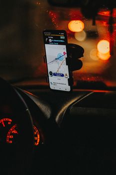 Nighttime view of GPS navigation on a phone in a car, displaying a map.
