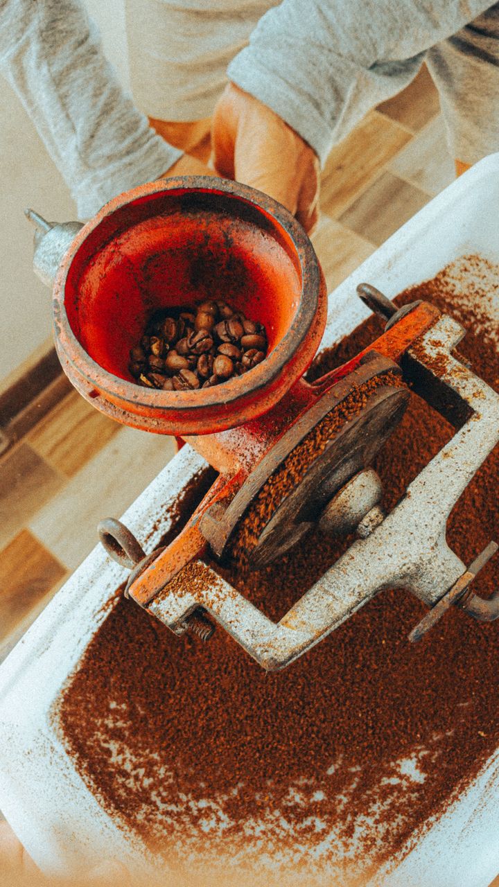 brass vintage manual coffee grinder sitting on a wooden coffee bar counter