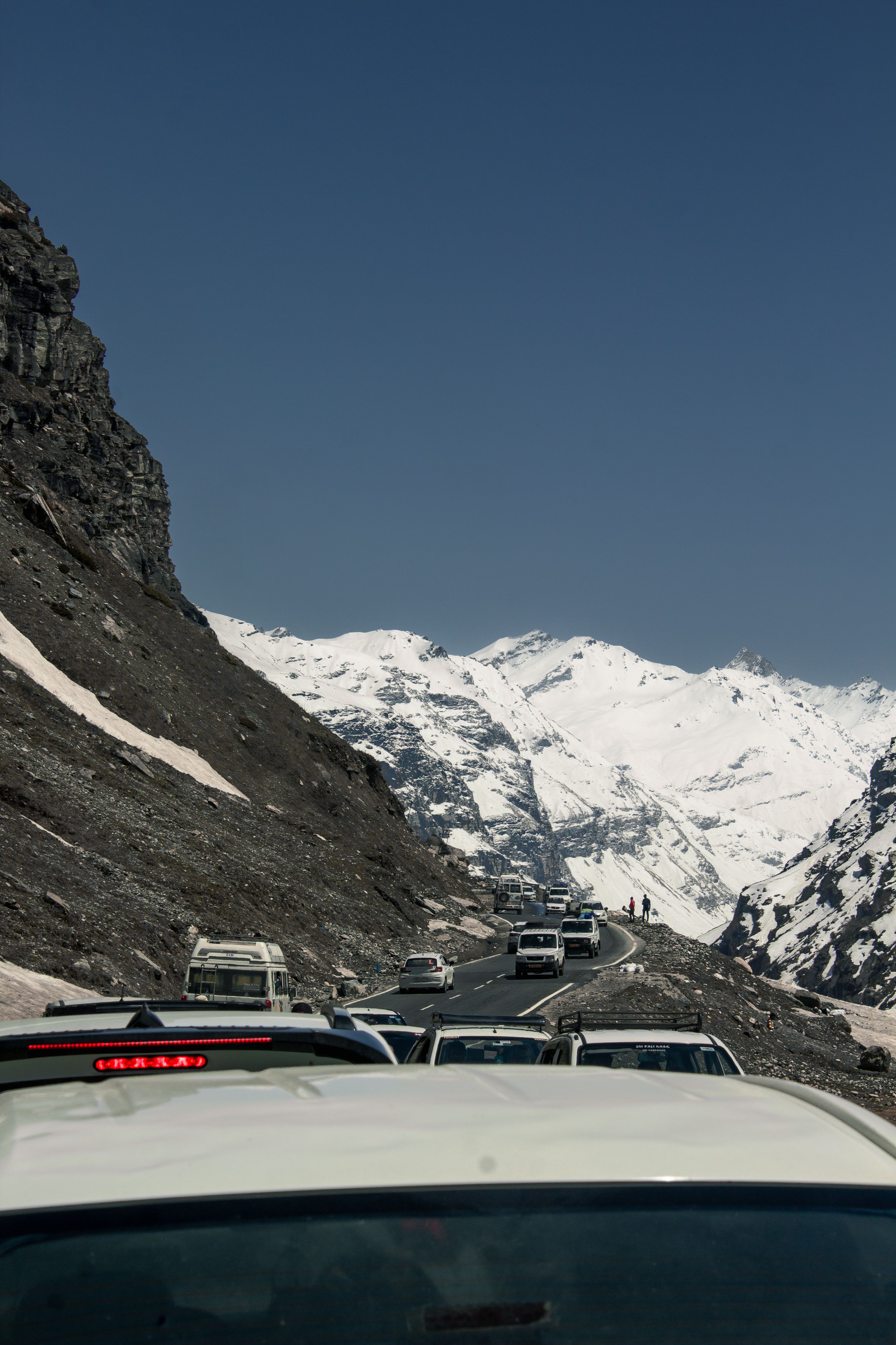 Scenic Mountain Road with Snowy Peaks and Vehicles · Free Stock Photo