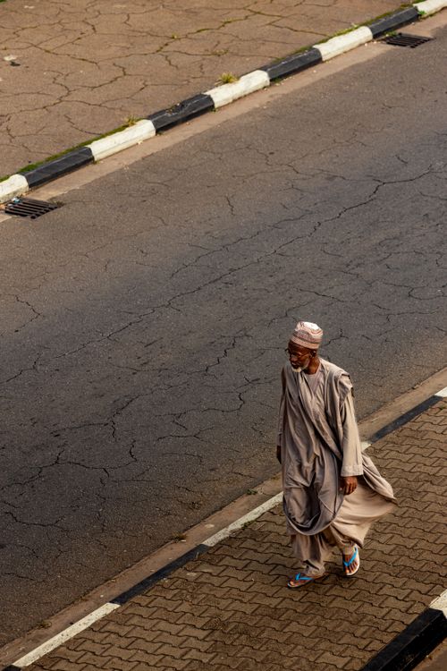 Free A man in traditional attire walking on a quiet street in Abuja, Nigeria. Stock Photo