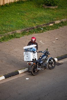 Motorcycle delivery driver on a city street in Abuja, Nigeria.