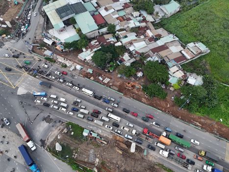 Aerial perspective of a busy road with heavy traffic and urban housing in Ho Chi Minh City, Vietnam.