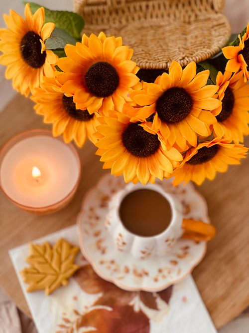 Free A warm autumn setting with sunflowers, coffee, candle, and leaves. Stock Photo