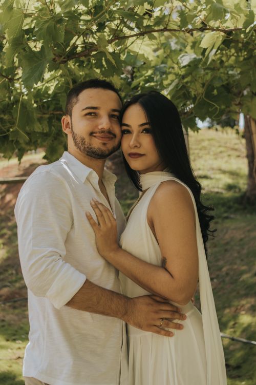 Free A couple embraces tenderly outdoors under lush green leaves in daylight. Stock Photo
