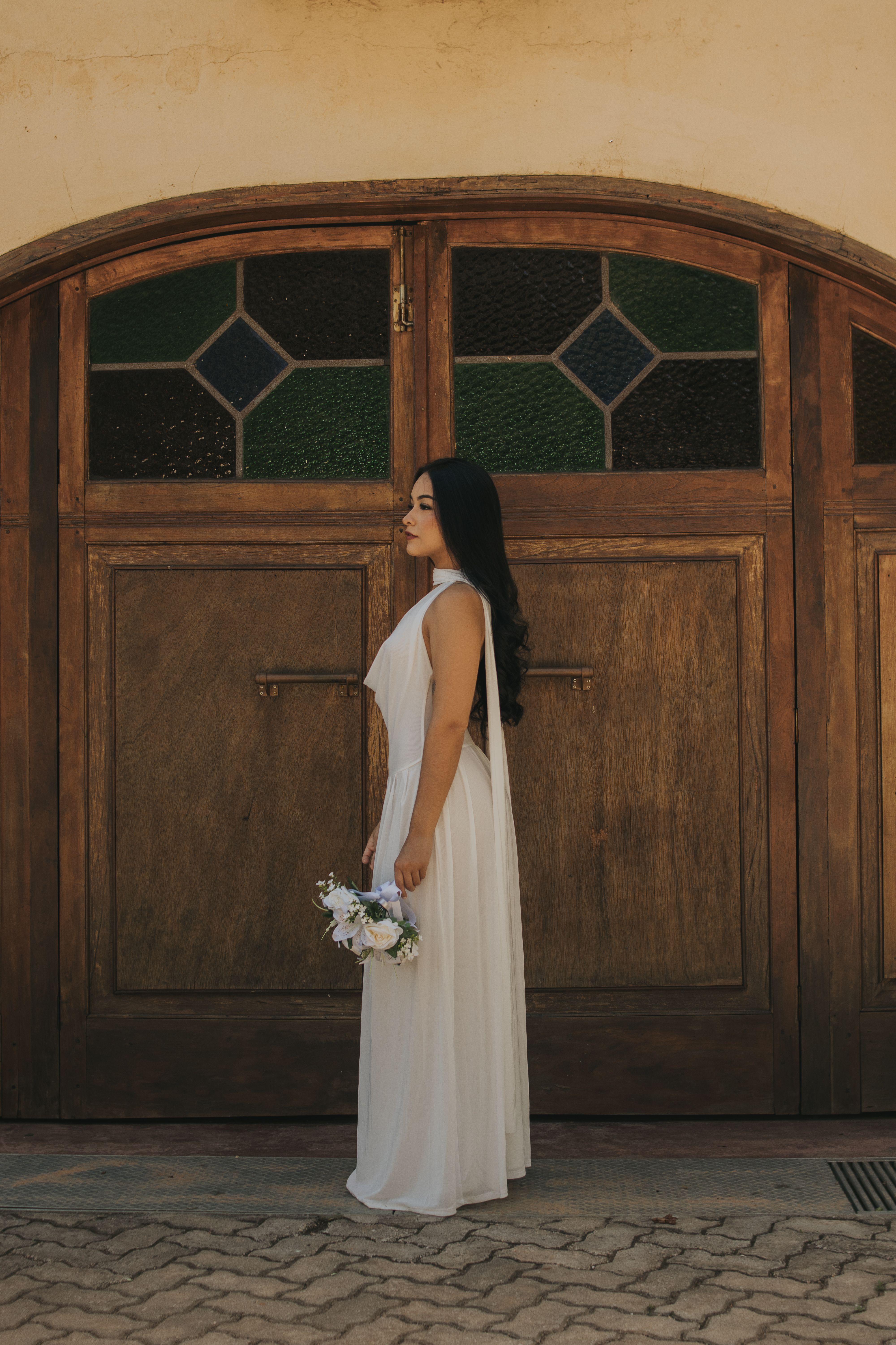Bridal portrait of a woman holding flowers against a rustic wooden door background.