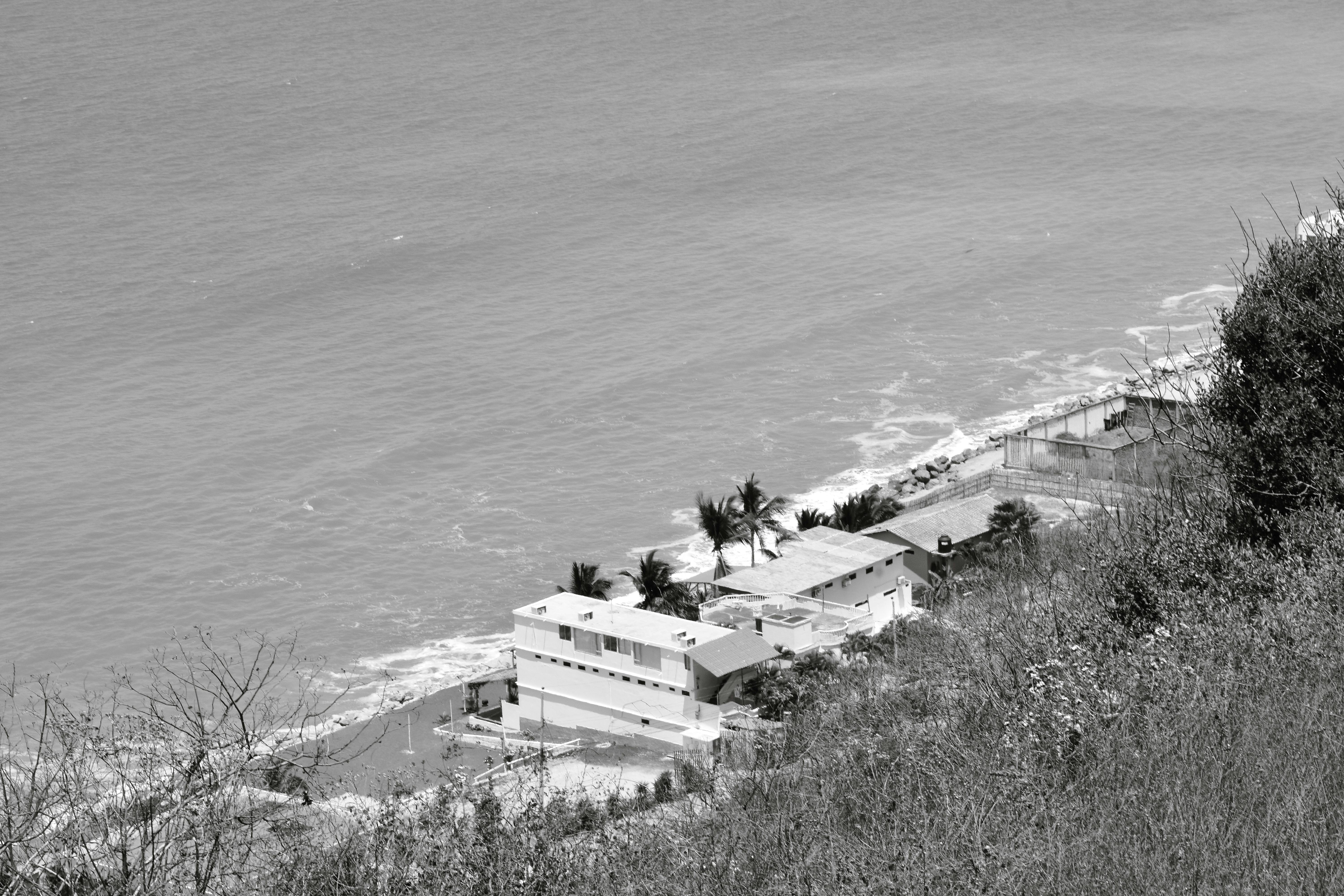 Aerial view of coastal buildings by the ocean in Ecuador, captured in black and white.