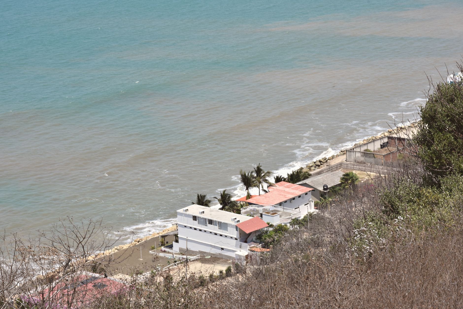 Panoramic aerial shot of beachside houses on the coast of Ecuador with ocean view.