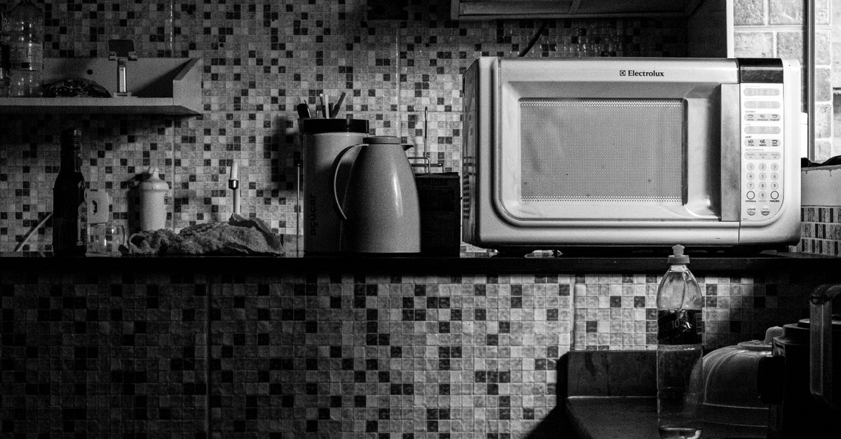 Cena de cozinha em preto e branco com um micro-ondas Electrolux e vários itens de cozinha, perfeita para temas de estilo de vida doméstico.