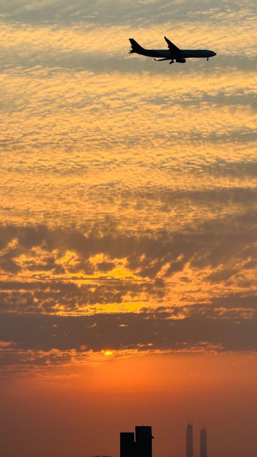 Free A plane flies over a city skyline during a vivid and colorful sunset. Stock Photo