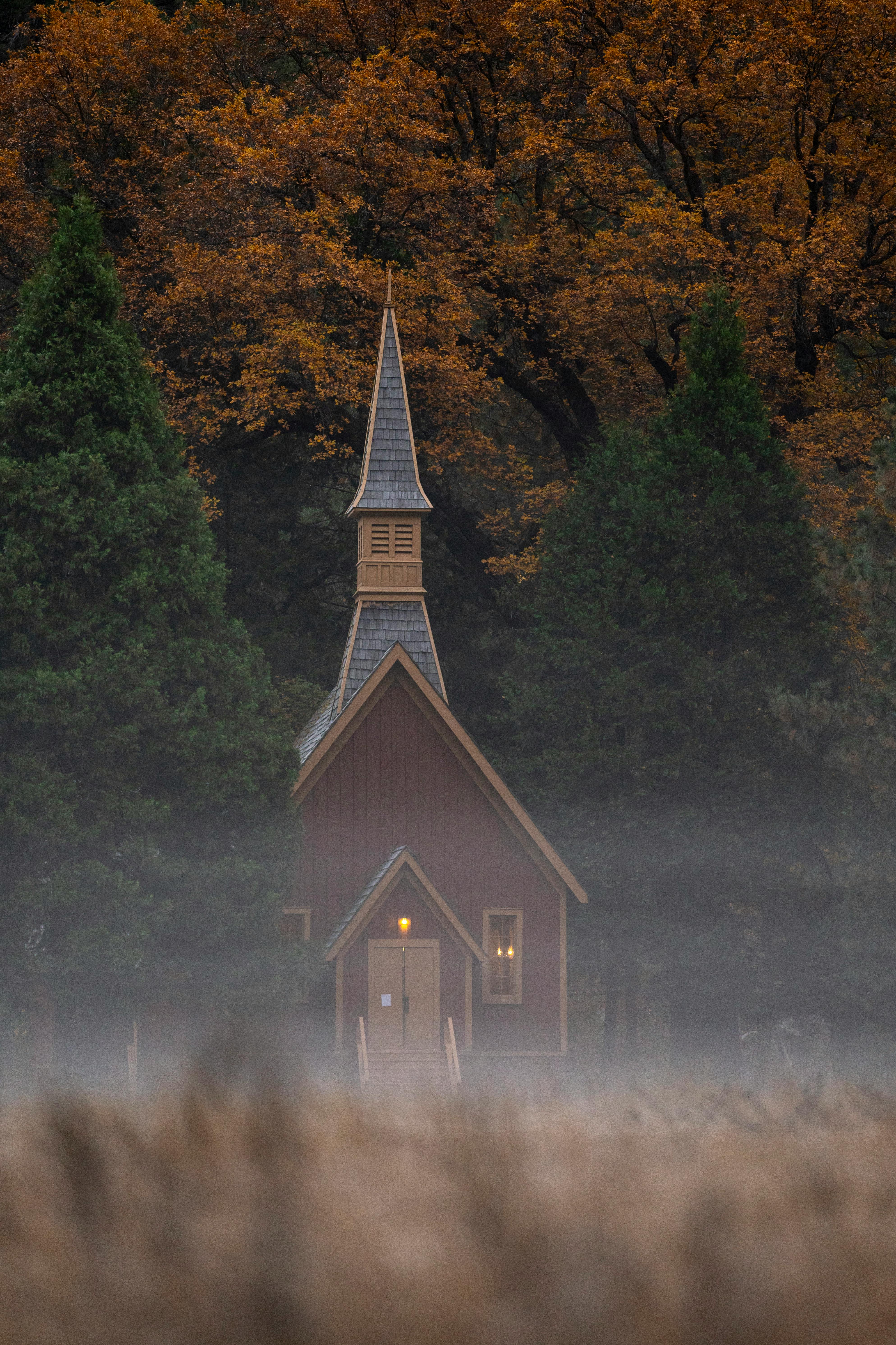 Idyllic chapel surrounded by autumn trees and mist, creating a serene atmosphere.