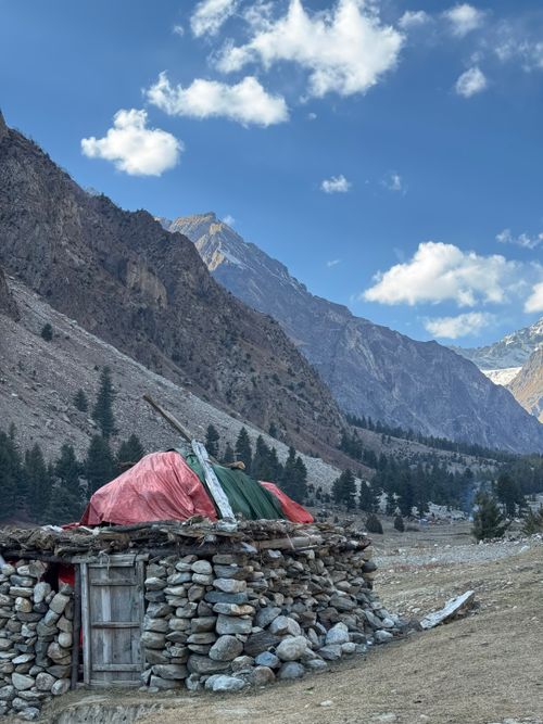 Free A stone hut nestled in a serene mountain valley under a clear blue sky. Stock Photo