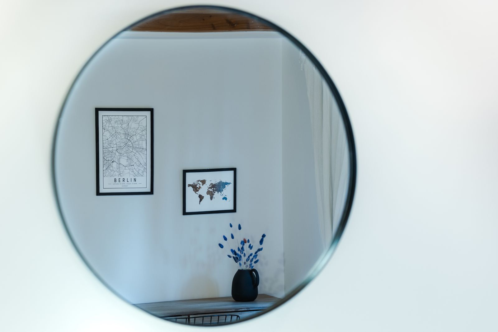 A round black-framed mirror on a white wall