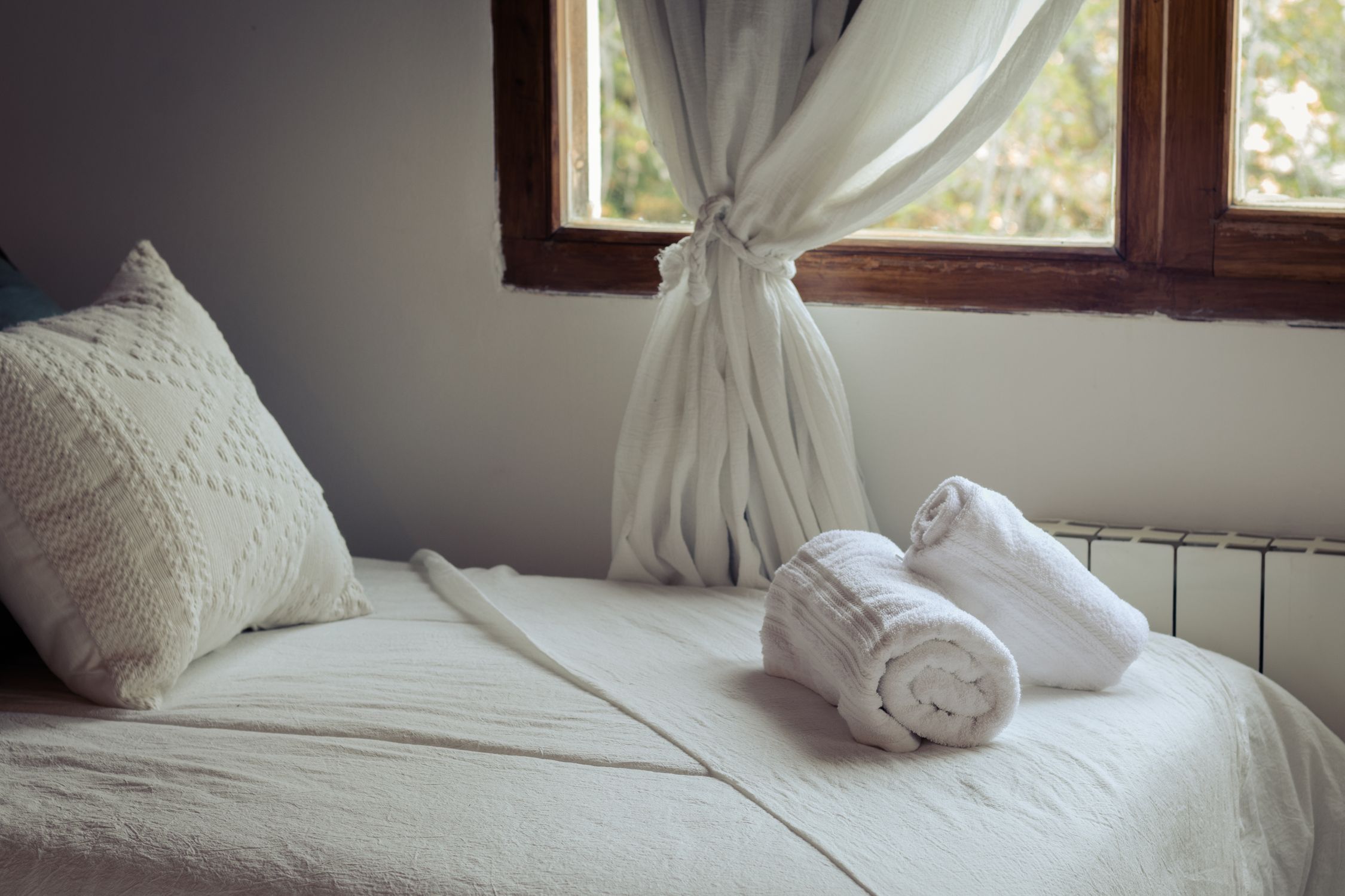 Inviting minimalist bedroom interior in San Carlos de Bariloche, featuring soft pillows and towels on a neatly made bed.