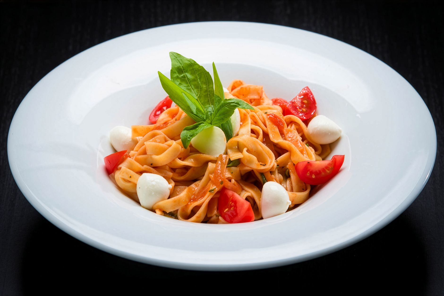 Bowl of pasta with tomatoes, salami and smoked mozzarella
