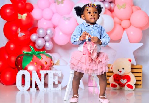 Free Adorable toddler girl surrounded by colorful balloons at her first birthday party. Stock Photo