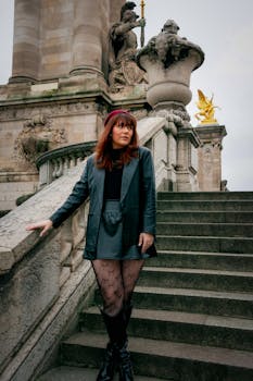 Elegant woman in autumn outfit posing on historic stairs in Paris. Editorial style with architectural backdrop.