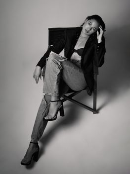 Black and white portrait of a woman in stylish attire sitting on a chair.
