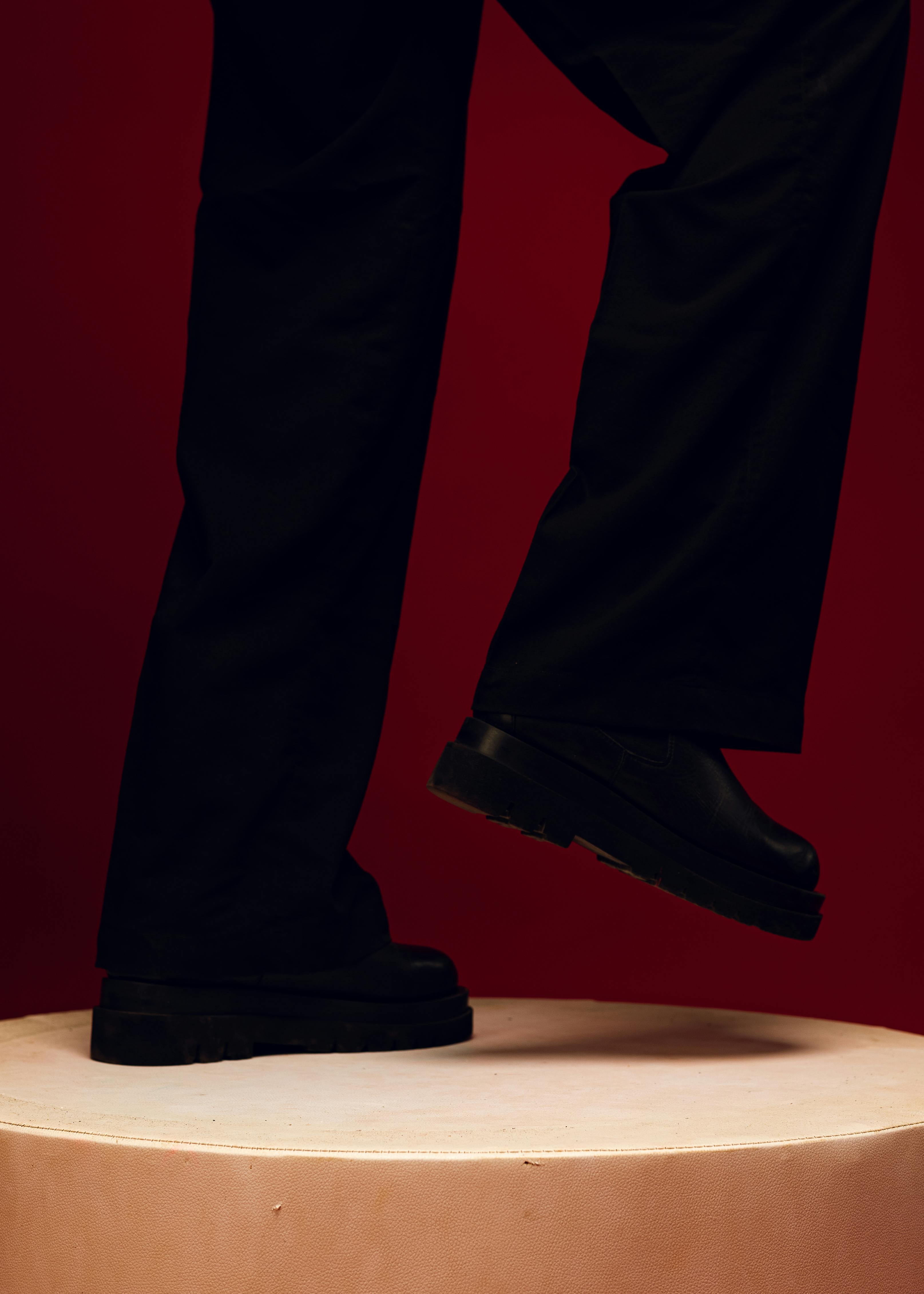 Gratis Gambar bergaya kaki dan sepatu melangkah ke podium putih dengan latar belakang merah. Foto Stok