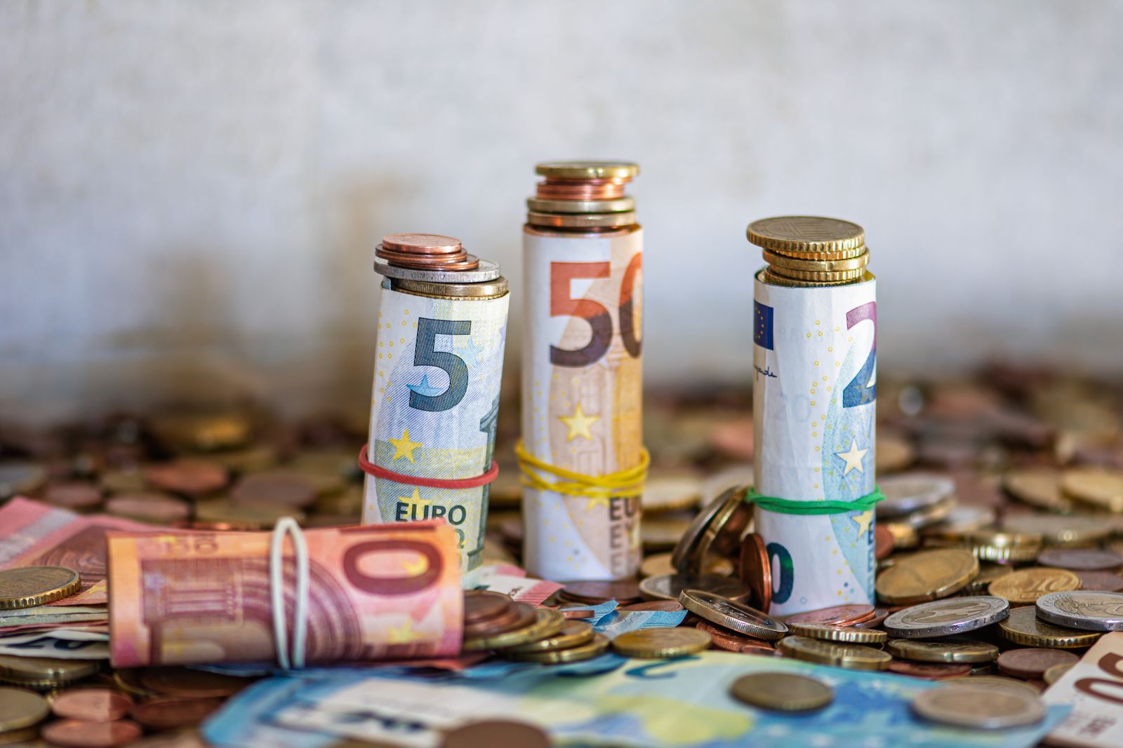 Billets en euros enroulés surmontés de pièces de monnaie, image d'une épargne en euros