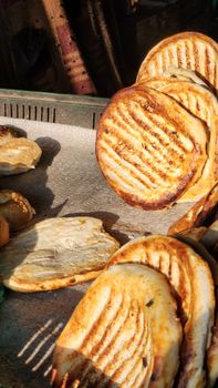 Crisp, golden bread rolls freshly grilled at an outdoor street market.