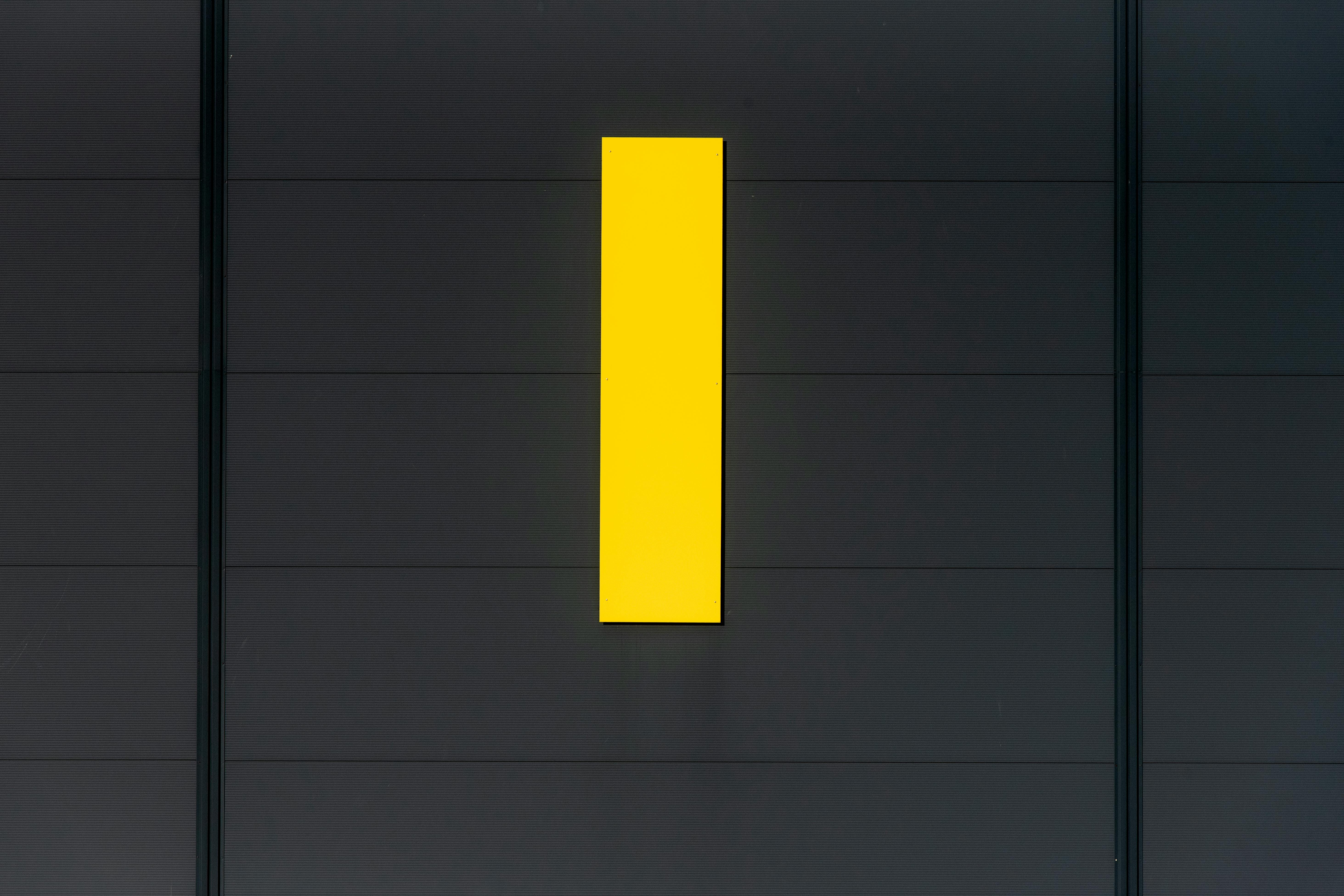 Gratis En minimalistisk komposition, der fremviser et lyst gult rektangel mod en mørk væg, der understreger kontrast og enkelhed. Lagerfoto