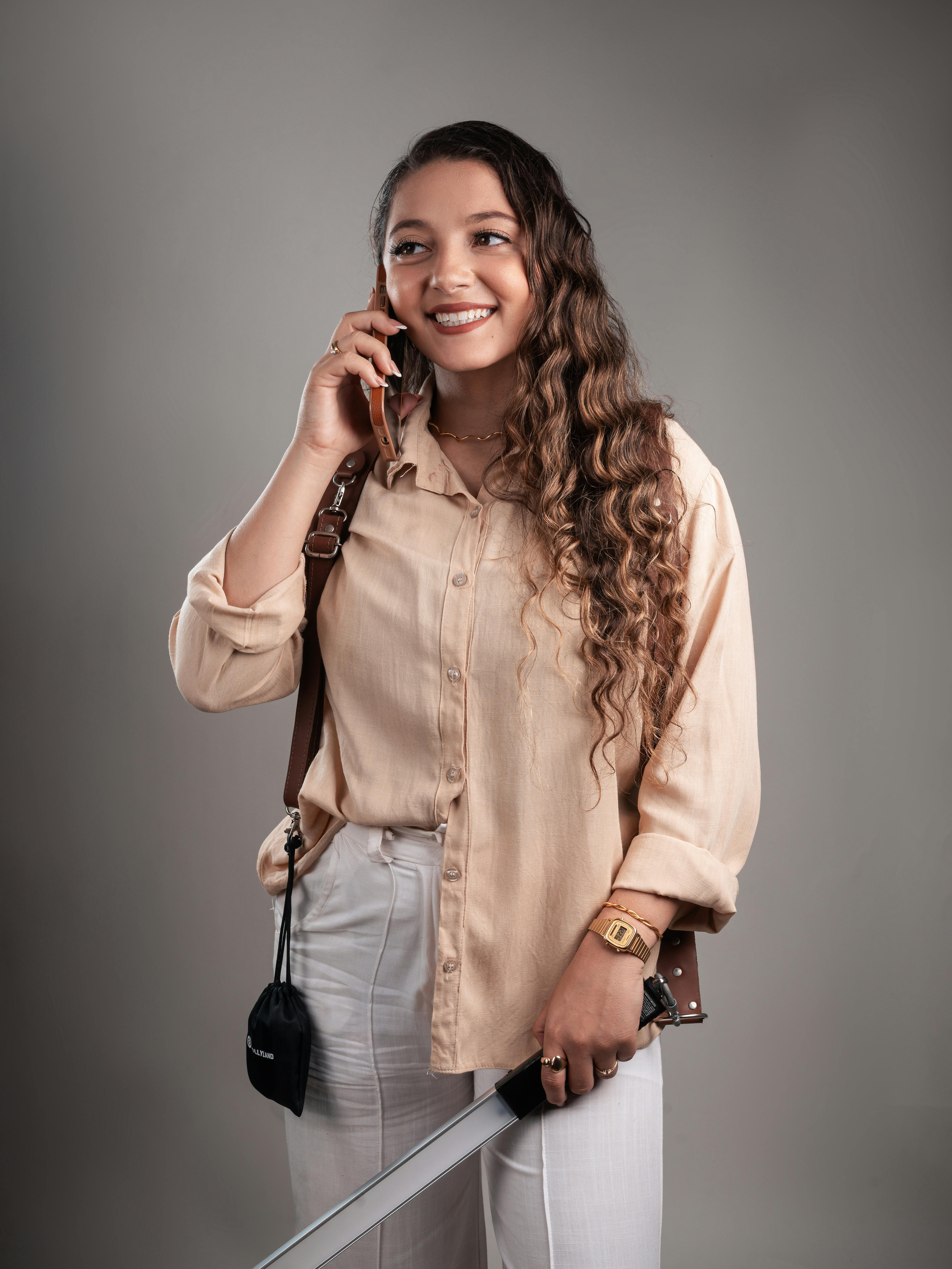 bezplatná Portrét usmívající se ženy s mečem a mobilním telefonem v ateliérovém prostředí. Základová fotografie