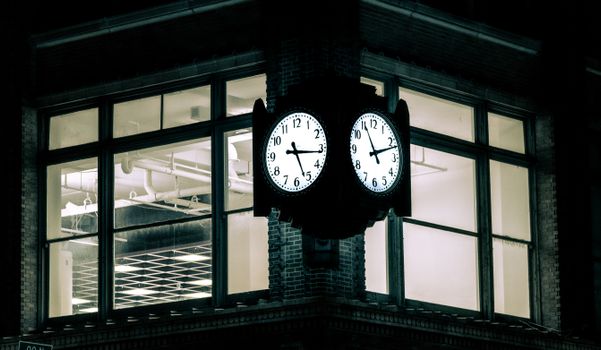 A vintage clock illuminated at night on a corner building in Indianapolis, Indiana.