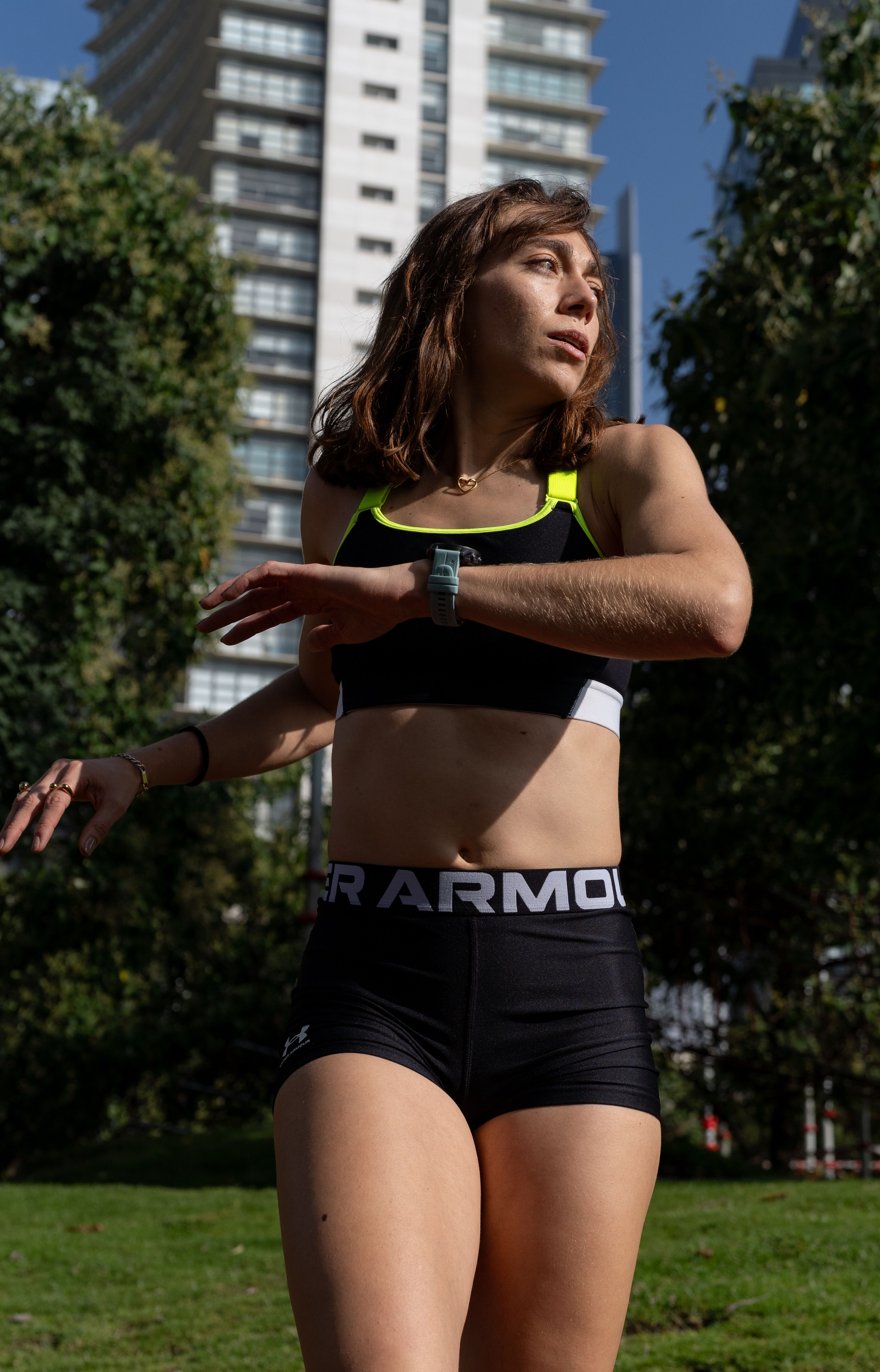 Young woman in sportswear jogging in a sunny city park.